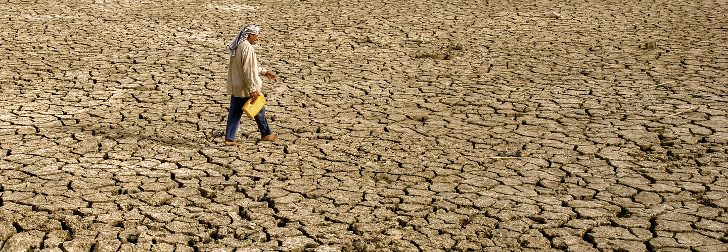 Photo of a man walking through dry, barren landscape