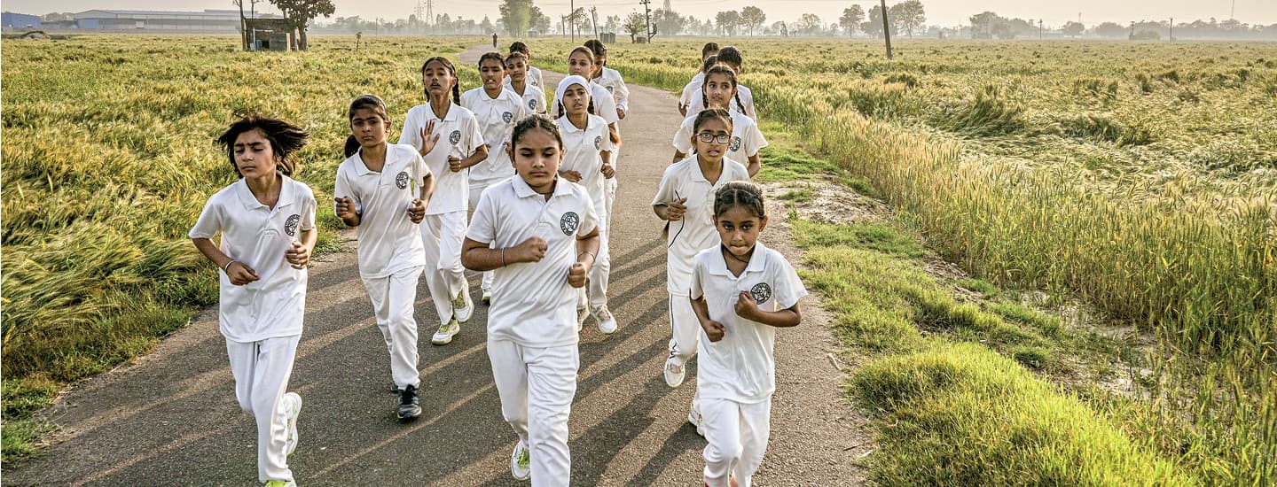 Photo of young cricket players running on a road in India